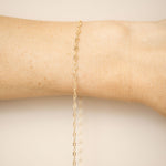 Gold bracelet on a person's wrist against a beige background