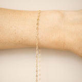 Gold bracelet on a person's wrist against a beige background