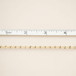 Gold chain on a beige fabric background with a ruler for scale.