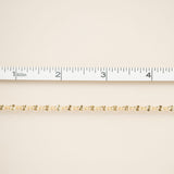 Gold chain on a beige fabric background with a ruler for scale.