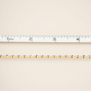 Gold chain on a beige fabric background with a ruler for scale.
