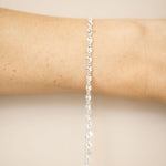 Silver bracelet on a person's wrist against a beige background