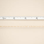 Gold chain on a beige fabric background with a ruler at the top.
