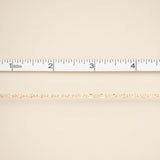 Gold chain on a beige fabric background with a ruler at the top.