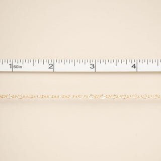 Gold chain on a beige fabric background with a ruler at the top.