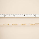 Gold chain with a ruler for scale on a beige background