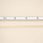Gold chain on a beige background with a ruler for scale