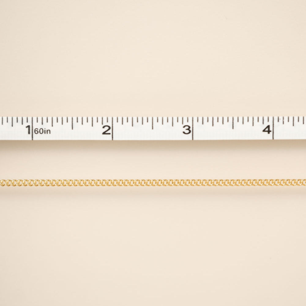 Gold chain on a beige background with a ruler for scale
