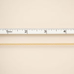 Gold chain on a beige background with a ruler for scale