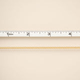 Gold chain on a beige background with a ruler for scale