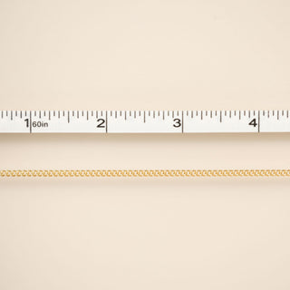 Gold chain on a beige background with a ruler for scale