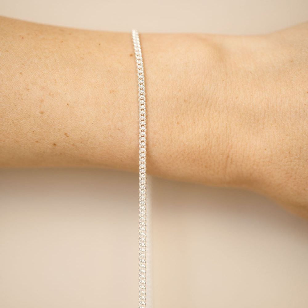 Silver bracelet on a person's wrist against a beige background