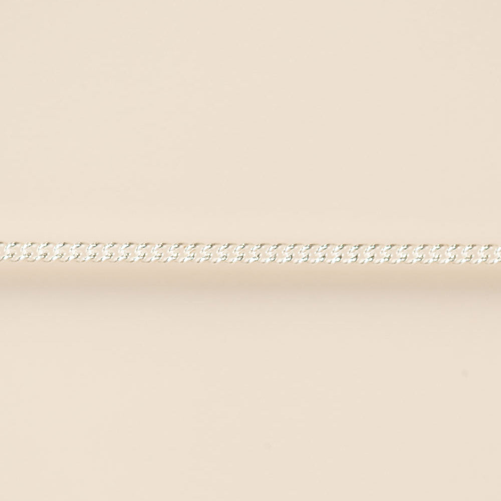 Thin silver chain on a beige background