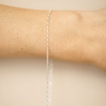 Silver bracelet on a person's wrist against a beige background