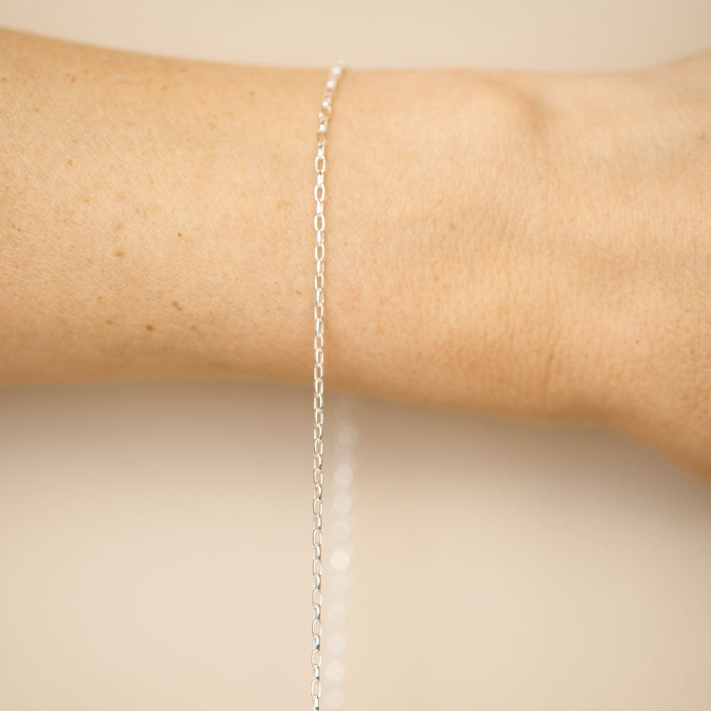Silver bracelet on a person's wrist against a beige background