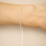 Silver bracelet on a person's wrist against a beige background