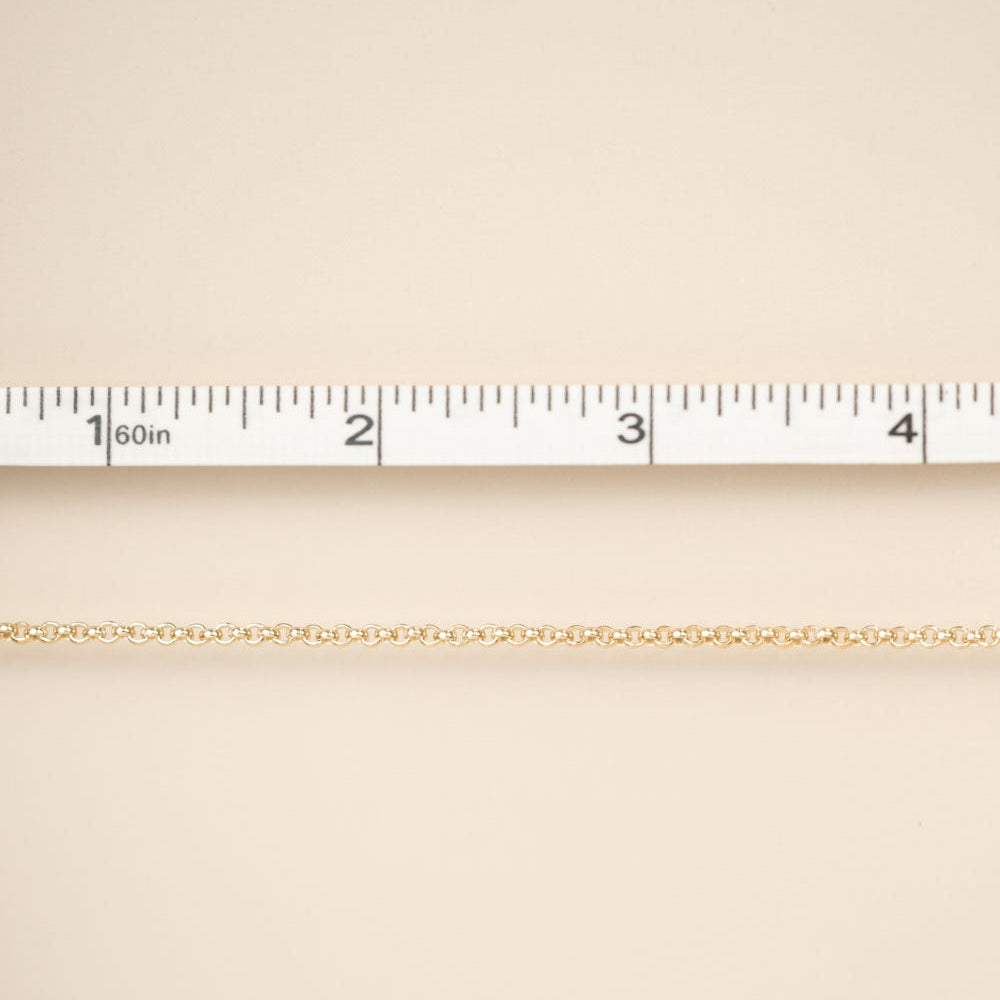 Gold chain on a beige fabric background with a ruler for scale.