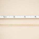 Gold chain on a beige fabric background with a ruler for scale.