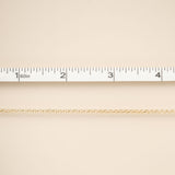 Gold chain on a beige fabric background with a ruler for scale.