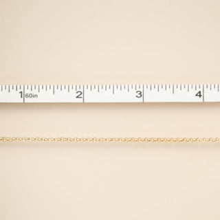 Gold chain on a beige fabric background with a ruler for scale.