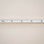 Gold chain with a ruler for scale on a beige background