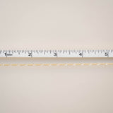 Gold chain with a ruler for scale on a beige background