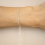 Silver bracelet on a person's wrist against a beige background