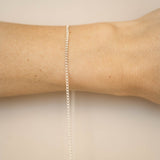 Silver bracelet on a person's wrist against a beige background