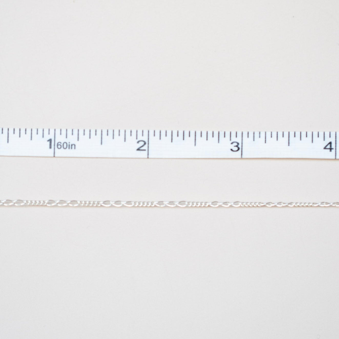 Gold chain next to a ruler on a white background