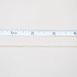 Gold chain next to a ruler on a white background