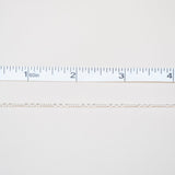 Gold chain next to a ruler on a white background