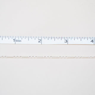 Gold chain next to a ruler on a white background