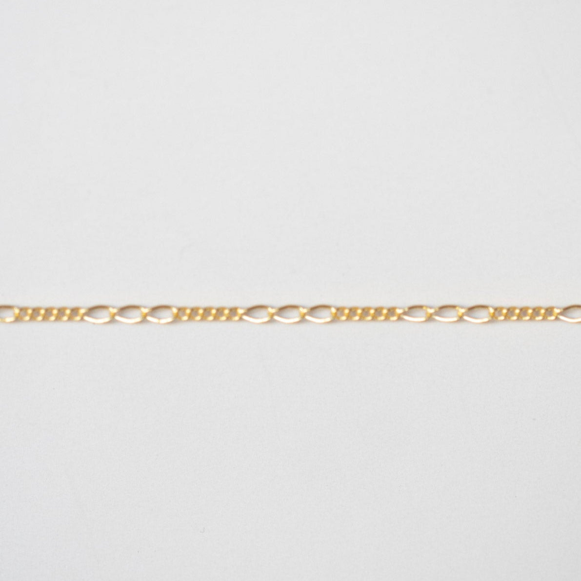 Gold chain on a light gray background
