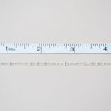 White fabric swatch with a ruler at the bottom for scale