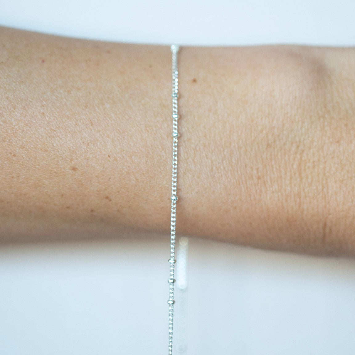 Silver bracelet on a person's wrist against a white background