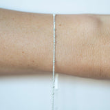 Silver bracelet on a person's wrist against a white background