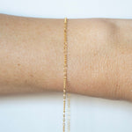 Gold bracelet on a person's wrist against a white background