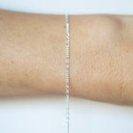 Silver chain necklace on a person's wrist against a white background
