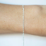 Silver chain necklace on a person's wrist against a white background
