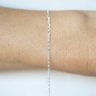 Silver chain necklace on a person's wrist against a white background