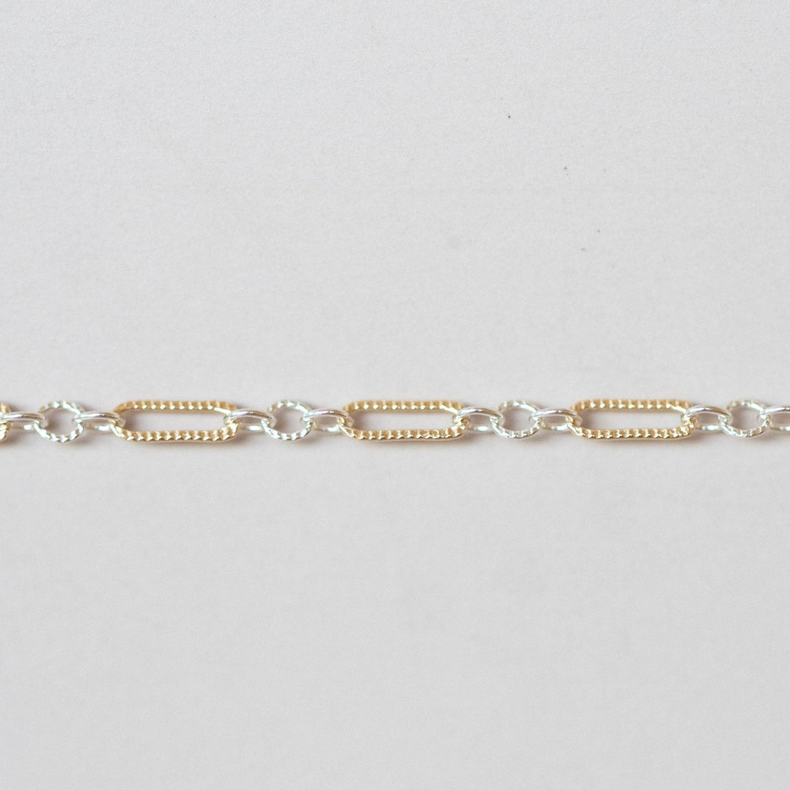 Gold and silver chain bracelet on a light gray background