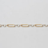 Gold and silver chain bracelet on a light gray background