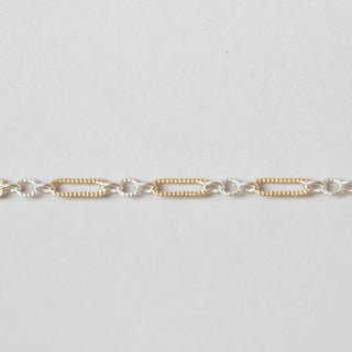 Gold and silver chain bracelet on a light gray background