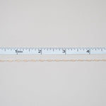 Thin beige thread on a white background with a ruler for scale.