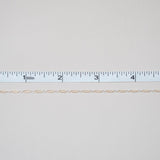 Thin beige thread on a white background with a ruler for scale.