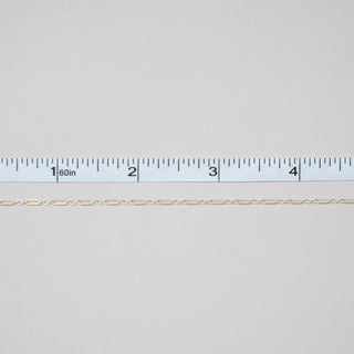 Thin beige thread on a white background with a ruler for scale.