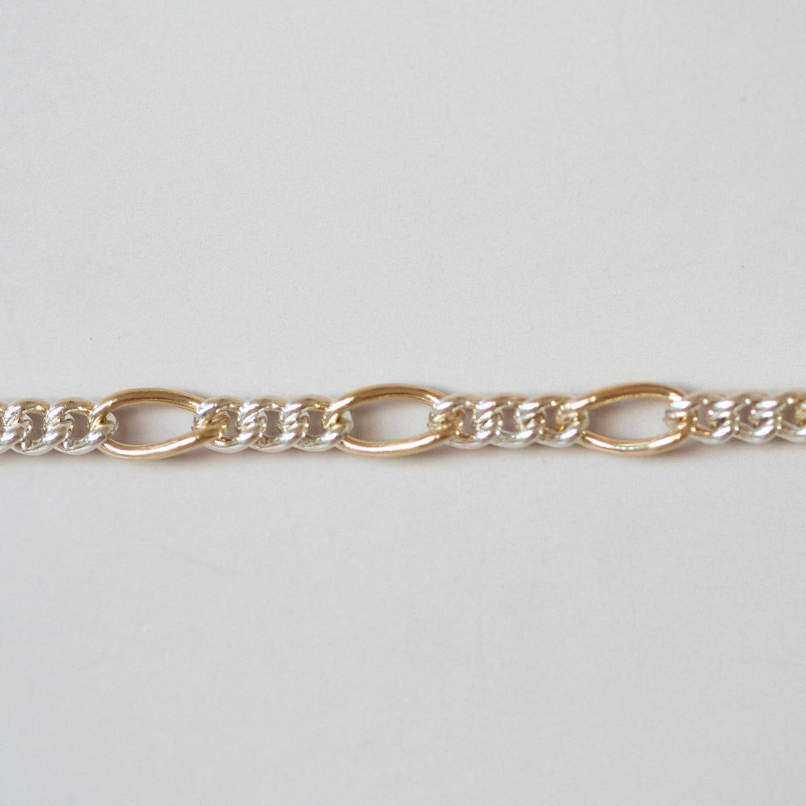 Gold chain bracelet on a light gray background