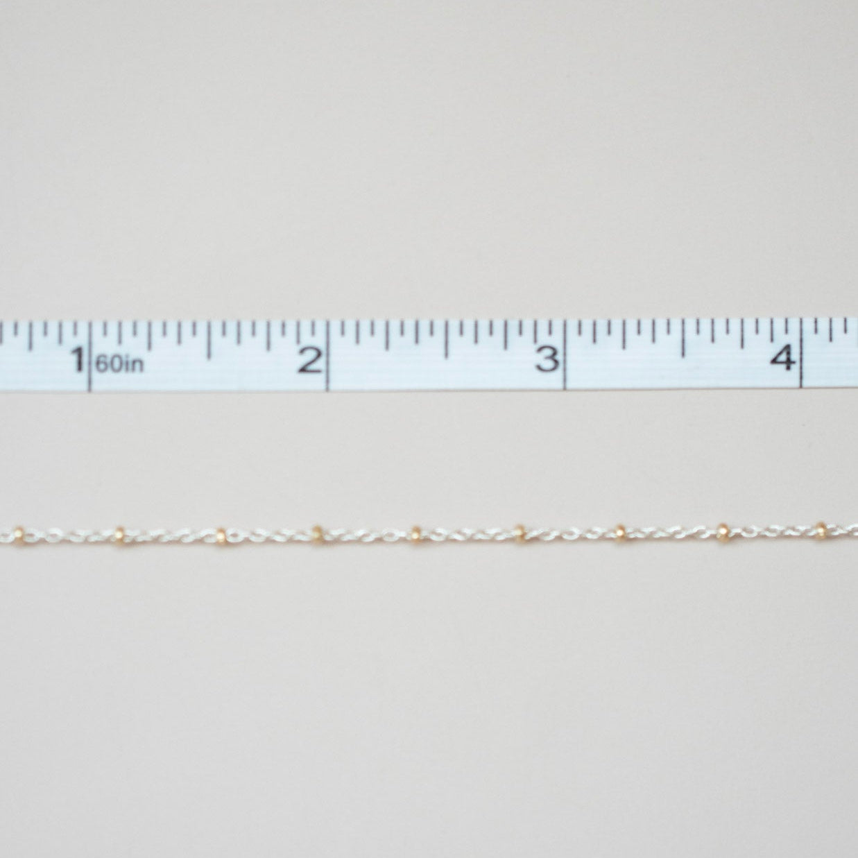 Gold chain with a ruler on a light gray background