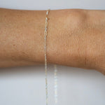 Gold chain bracelet on a wrist against a white background