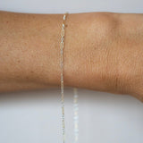Gold chain bracelet on a wrist against a white background
